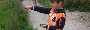 Foto: Ett barn med mobil och hörlurar pekar framåt